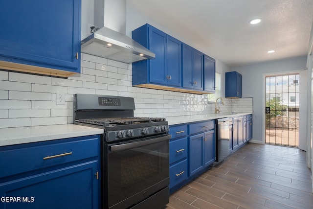 3411 Memphis Ave, El Paso, TX 79930 - kitchen with gas range, wall chimney range hood, blue cabinetry, stainless steel dishwasher, and light countertops