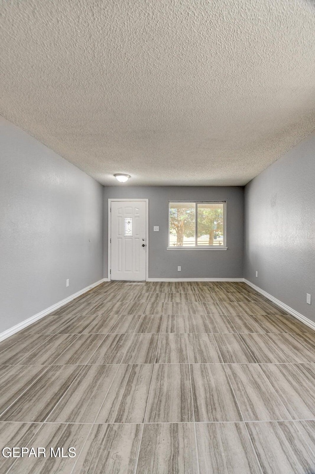 10712 Georgetown St, El Paso, TX 79924 - unfurnished living room featuring a textured ceiling and baseboards