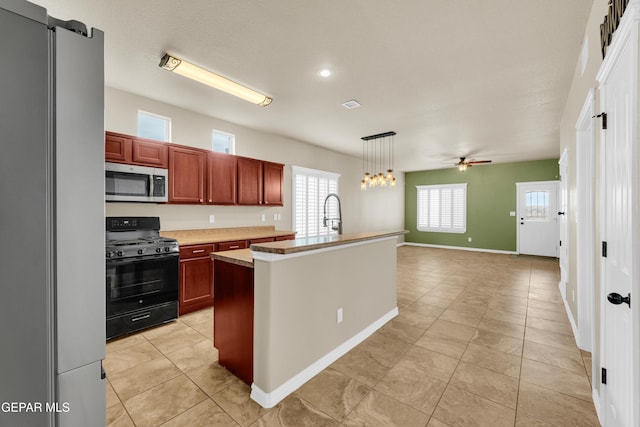 2937 Pino Triste Dr, El Paso, TX 79938 - kitchen featuring freestanding refrigerator, black gas range oven, stainless steel microwave, light countertops, and light tile patterned flooring
