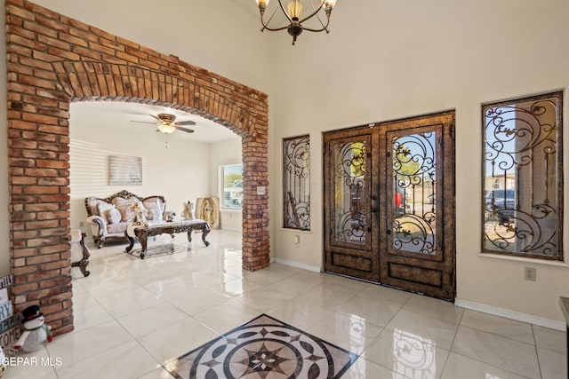 10728 Regina Dr, Socorro, TX 79927 - entrance foyer featuring arched walkways, light tile patterned floors, a chandelier, a ceiling fan, and a towering ceiling