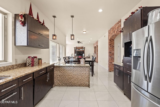 10728 Regina Dr, Socorro, TX 79927 - kitchen with stainless steel refrigerator with ice dispenser, open floor plan, light tile patterned floors, dark brown cabinets, and hanging light fixtures