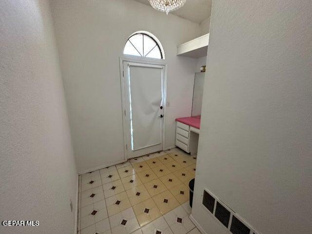 2129 Noviembre Dr, El Paso, TX 79935 - foyer featuring light tile patterned flooring, a chandelier, and a textured wall