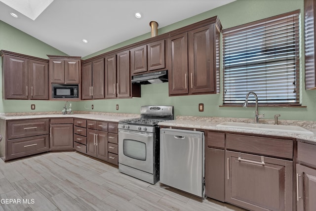 12249 Holy Springs Ct, El Paso, TX 79928 - kitchen with stainless steel appliances, a skylight, under cabinet range hood, lofted ceiling, and dark brown cabinetry