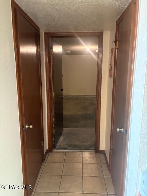 10700 Janway Dr, El Paso, TX 79935 - hallway featuring a textured ceiling and light tile patterned floors