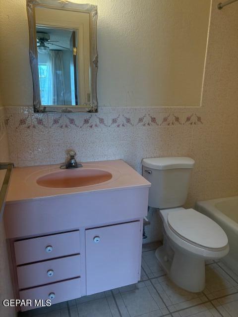 10700 Janway Dr, El Paso, TX 79935 - full bathroom featuring vanity, a bath, tile walls, tile patterned floors, and a wainscoted wall