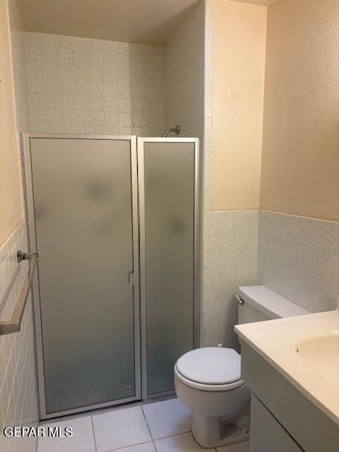 10700 Janway Dr, El Paso, TX 79935 - bathroom featuring tile walls, vanity, tile patterned flooring, a stall shower, and wainscoting