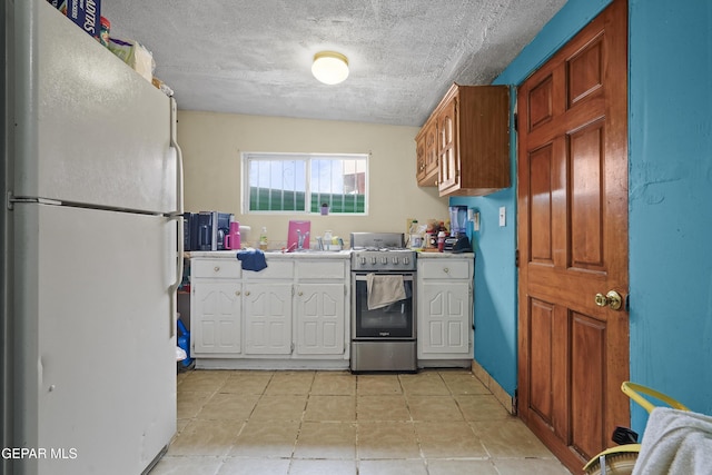 204 Ruth St, Anthony, NM 88021 - kitchen with freestanding refrigerator, stainless steel range with gas cooktop, white cabinetry, light countertops, and light tile patterned floors