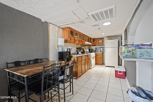 204 Ruth St, Anthony, NM 88021 - kitchen with white appliances, brown cabinets, light countertops, light tile patterned flooring, and glass insert cabinets