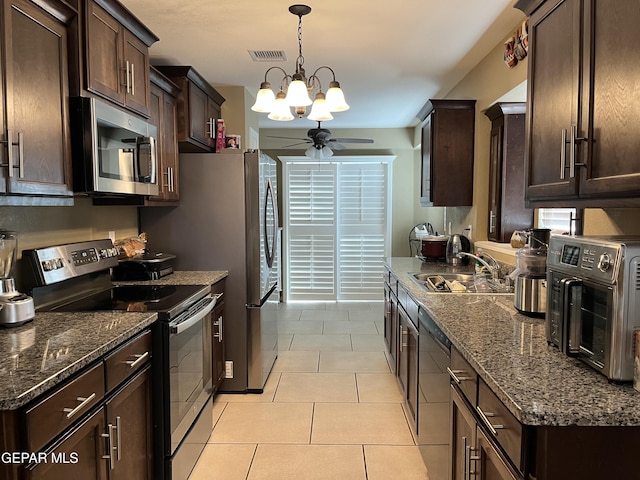 11128 Colbert Coldwell Ln, Socorro, TX 79927 - kitchen with stainless steel appliances, a ceiling fan, dark brown cabinetry, a chandelier, and dark stone countertops