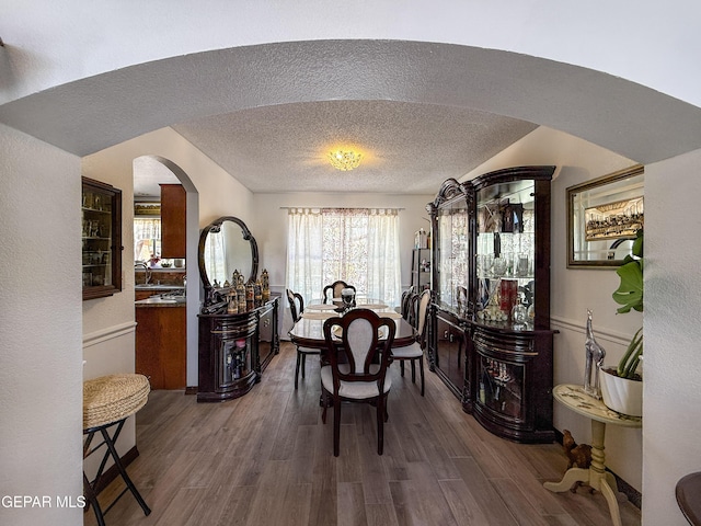 14177 Spanish Point Dr, El Paso, TX 79938 - dining space with arched walkways, dark wood-type flooring, and a textured ceiling