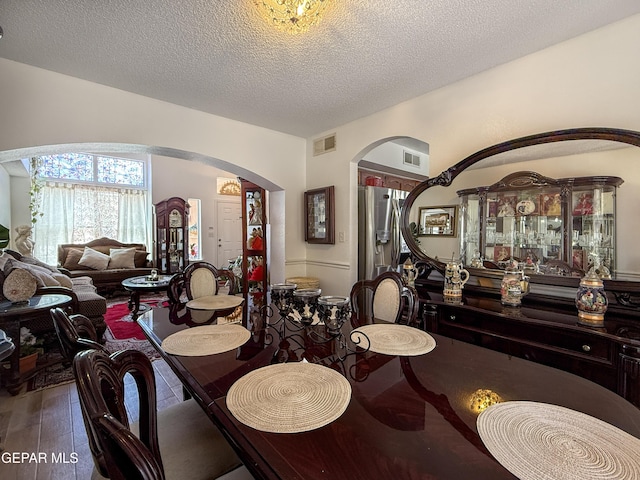 14177 Spanish Point Dr, El Paso, TX 79938 - dining area featuring arched walkways, wood finished floors, and a textured ceiling