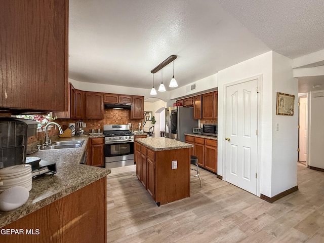 14177 Spanish Point Dr, El Paso, TX 79938 - kitchen featuring stainless steel appliances, under cabinet range hood, backsplash, light wood-style floors, and a kitchen island
