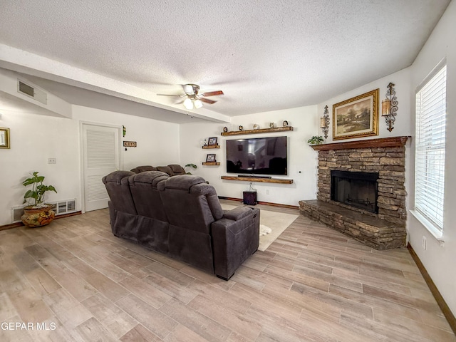 14177 Spanish Point Dr, El Paso, TX 79938 - living area with a textured ceiling, a ceiling fan, light wood-style floors, and a stone fireplace