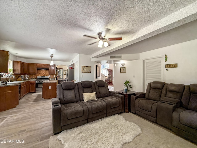 14177 Spanish Point Dr, El Paso, TX 79938 - living room featuring ceiling fan, a textured ceiling, arched walkways, and light wood-type flooring