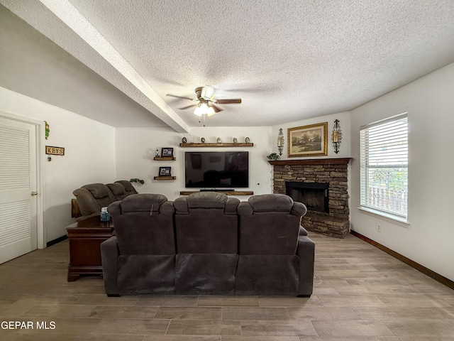 14177 Spanish Point Dr, El Paso, TX 79938 - living room featuring a textured ceiling, a ceiling fan, light wood finished floors, and a fireplace