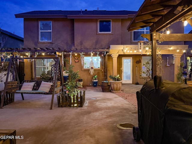 14177 Spanish Point Dr, El Paso, TX 79938 - back of house at night with a pergola, a patio area, and stucco siding