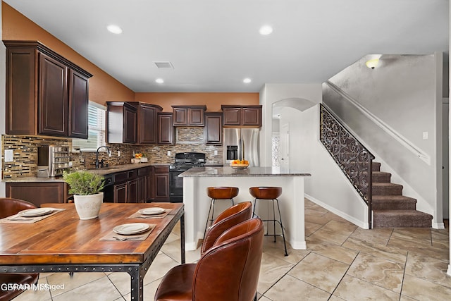 12326 Westbury, El Paso, TX 79928 - kitchen featuring stainless steel fridge, black gas range oven, dark brown cabinets, backsplash, and a kitchen island