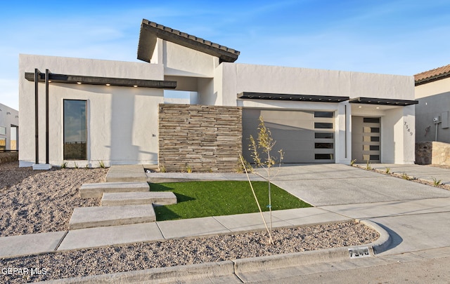 7349 Cimarron Rim Dr, El Paso, TX 79911 - contemporary house featuring concrete driveway, an attached garage, stucco siding, and stone siding