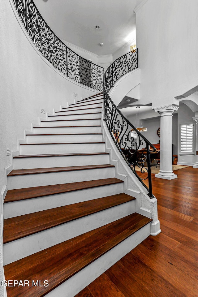 6528 Calle Placido Dr, El Paso, TX 79912 - staircase with ornate columns, a high ceiling, wood finished floors, and arched walkways