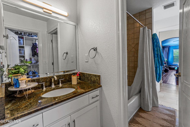 6528 Calle Placido Dr, El Paso, TX 79912 - bathroom featuring vanity, a textured wall, shower / bathtub combination with curtain, and wood finished floors
