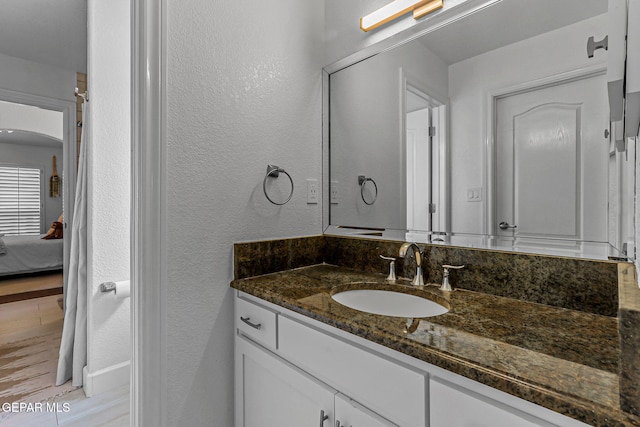 6528 Calle Placido Dr, El Paso, TX 79912 - ensuite bathroom featuring vanity, a textured wall, and wood finished floors