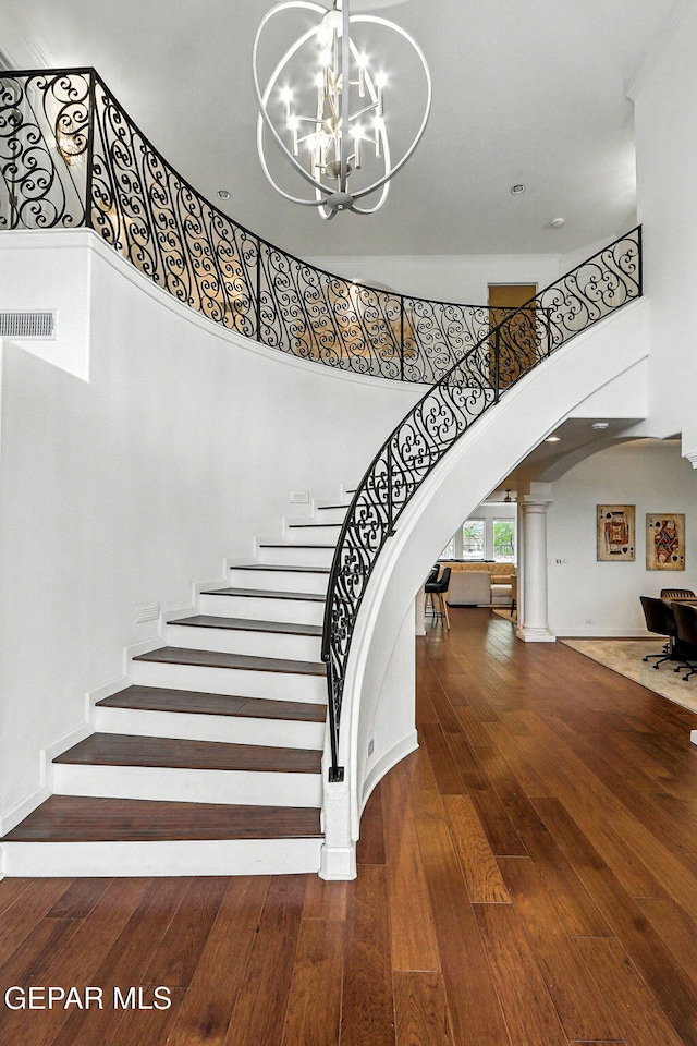 6528 Calle Placido Dr, El Paso, TX 79912 - stairway featuring arched walkways, ornate columns, a towering ceiling, hardwood / wood-style floors, and a chandelier