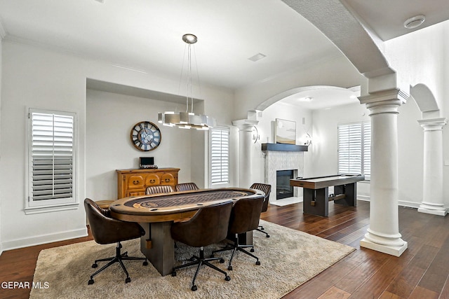 6528 Calle Placido Dr, El Paso, TX 79912 - dining area featuring a tiled fireplace, decorative columns, dark wood-style flooring, arched walkways, and crown molding