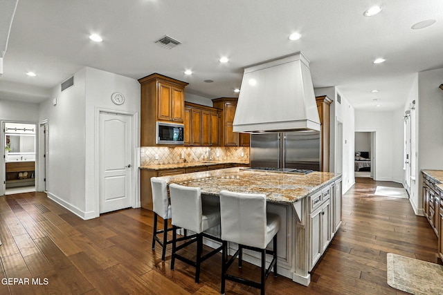 6528 Calle Placido Dr, El Paso, TX 79912 - kitchen featuring appliances with stainless steel finishes, light stone countertops, dark wood-type flooring, decorative backsplash, and a center island