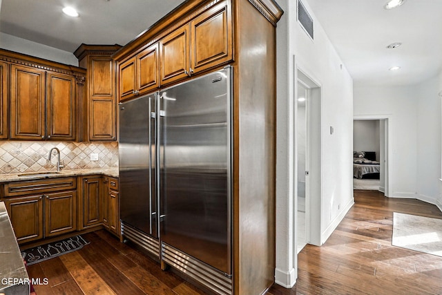 6528 Calle Placido Dr, El Paso, TX 79912 - kitchen featuring stainless steel built in refrigerator, dark wood finished floors, backsplash, light stone countertops, and brown cabinets