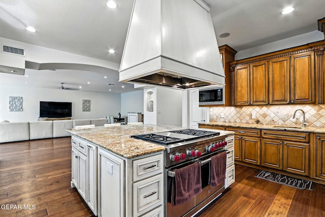 6528 Calle Placido Dr, El Paso, TX 79912 - kitchen with luxury stove, built in microwave, premium range hood, a kitchen island, and dark wood finished floors