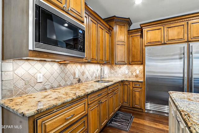 6528 Calle Placido Dr, El Paso, TX 79912 - kitchen featuring built in appliances, brown cabinets, light stone counters, dark wood-style floors, and decorative backsplash
