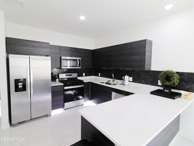 480 Deserts Dr, Socorro, TX 79927 - kitchen with stainless steel appliances, light countertops, a peninsula, decorative backsplash, and dark cabinetry