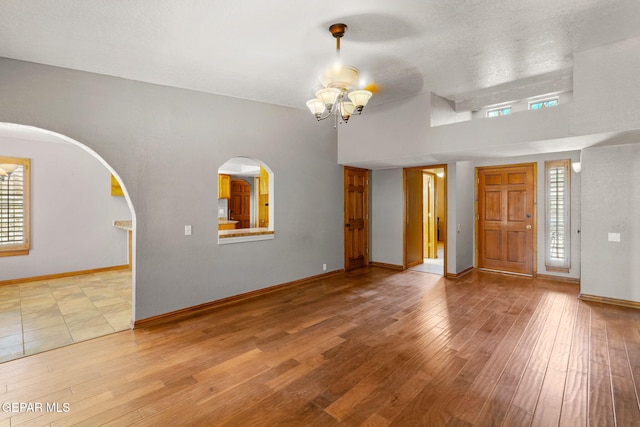 11852 Pete Rose Dr, El Paso, TX 79936 - unfurnished living room with wood finished floors, healthy amount of natural light, and a chandelier