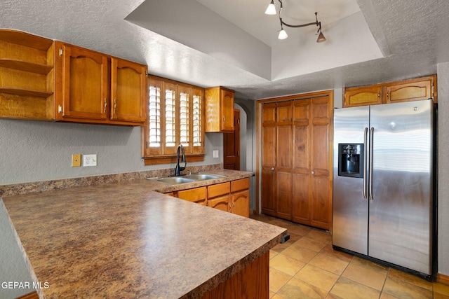 11852 Pete Rose Dr, El Paso, TX 79936 - kitchen with stainless steel fridge, arched walkways, brown cabinets, a textured ceiling, and a peninsula