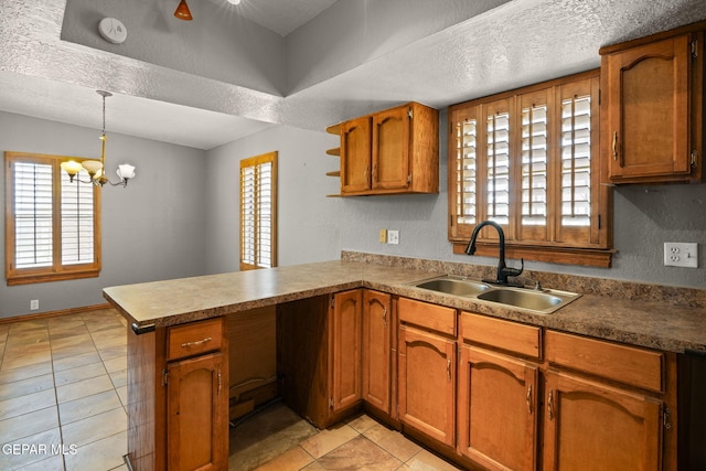 11852 Pete Rose Dr, El Paso, TX 79936 - kitchen featuring a peninsula, brown cabinets, light tile patterned flooring, healthy amount of natural light, and a textured ceiling