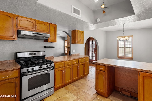 11852 Pete Rose Dr, El Paso, TX 79936 - kitchen with stainless steel gas range, under cabinet range hood, arched walkways, and brown cabinetry
