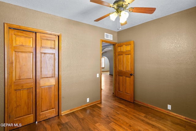 11852 Pete Rose Dr, El Paso, TX 79936 - unfurnished bedroom featuring a textured wall, dark wood-style flooring, arched walkways, a closet, and a ceiling fan