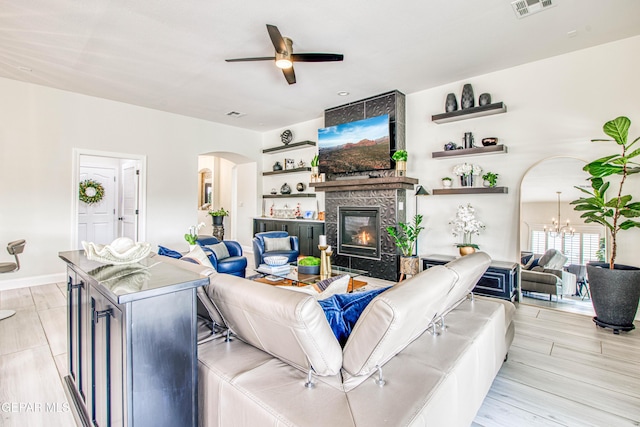 5705 Valley Lilac Ln, El Paso, TX 79932 - living area featuring arched walkways, a ceiling fan, a high end fireplace, light wood-style floors, and a chandelier