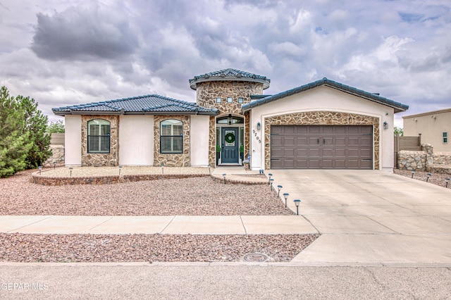 5705 Valley Lilac Ln, El Paso, TX 79932 - mediterranean / spanish house with stone siding, driveway, a tile roof, stucco siding, and an attached garage