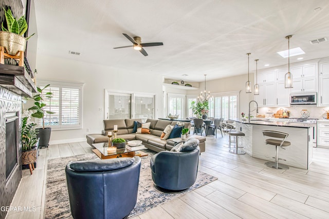 5705 Valley Lilac Ln, El Paso, TX 79932 - living area featuring a fireplace, a ceiling fan, light wood-type flooring, and a chandelier