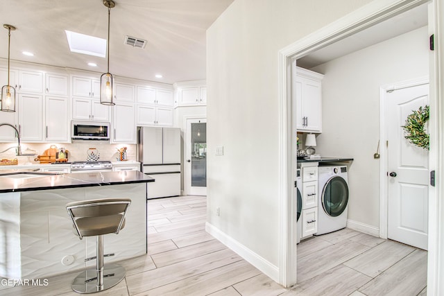 5705 Valley Lilac Ln, El Paso, TX 79932 - kitchen featuring white appliances, washer / dryer, dark countertops, white cabinets, and wood finish floors
