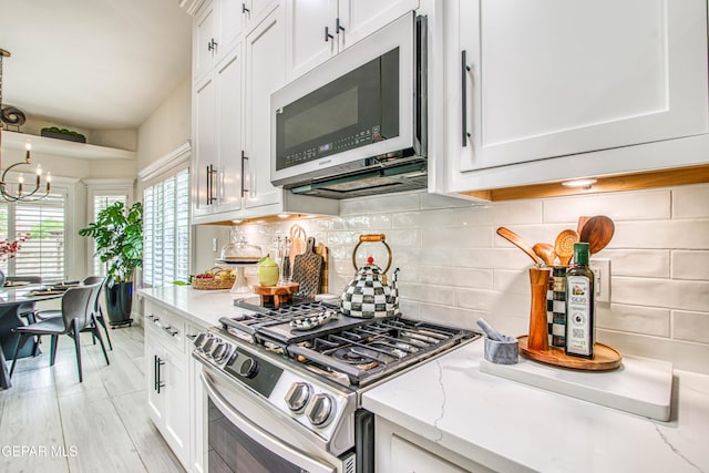 5705 Valley Lilac Ln, El Paso, TX 79932 - kitchen featuring stainless steel appliances, a chandelier, white cabinets, and tasteful backsplash