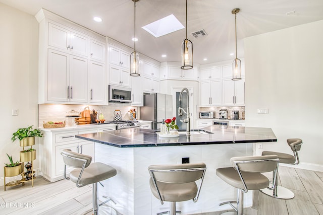 5705 Valley Lilac Ln, El Paso, TX 79932 - kitchen with white microwave, freestanding refrigerator, light wood-type flooring, a breakfast bar, and a skylight