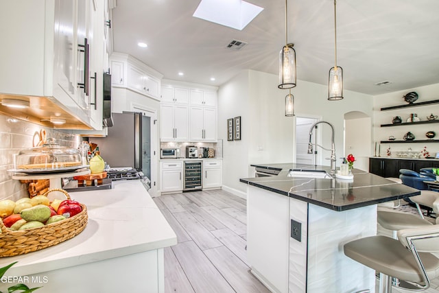 5705 Valley Lilac Ln, El Paso, TX 79932 - kitchen with beverage cooler, a kitchen bar, tasteful backsplash, white cabinets, and arched walkways