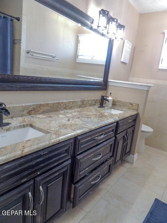 10945 Gary Player Dr, El Paso, TX 79935 - full bathroom with double vanity, tile patterned flooring, and a shower with shower curtain