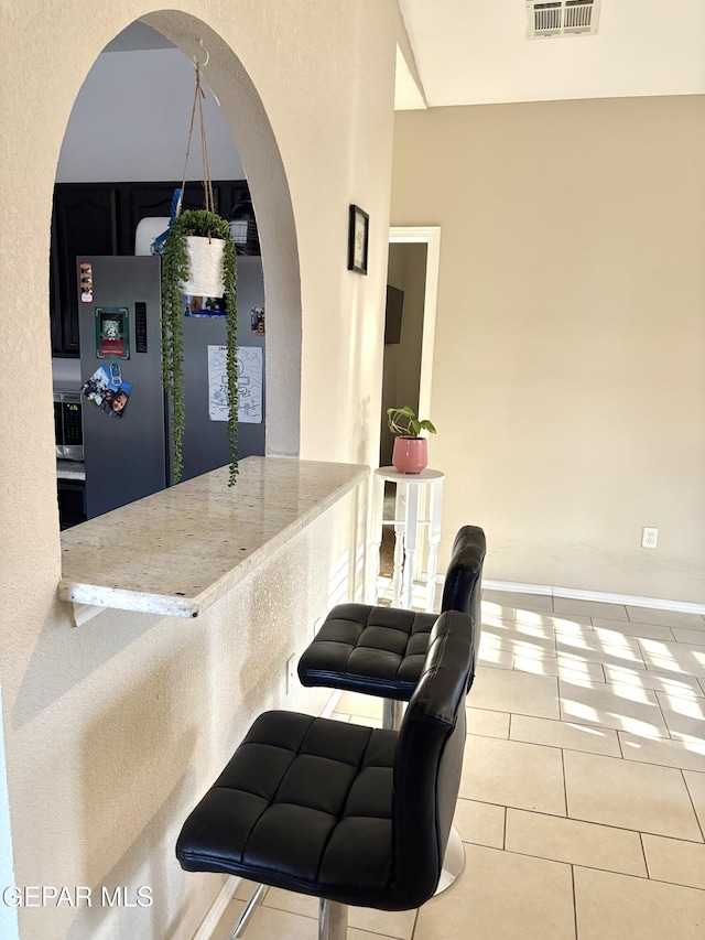 632 Manzanilla Pl, El Paso, TX 79928 - kitchen with arched walkways, tile patterned floors, freestanding refrigerator, and light stone countertops