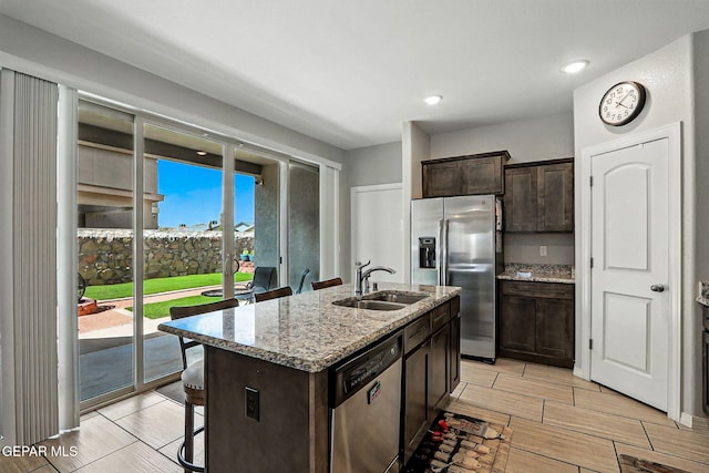 2116 Tim Foster St, El Paso, TX 79938 - kitchen featuring stainless steel appliances, a kitchen breakfast bar, dark brown cabinetry, light stone countertops, and a kitchen island with sink