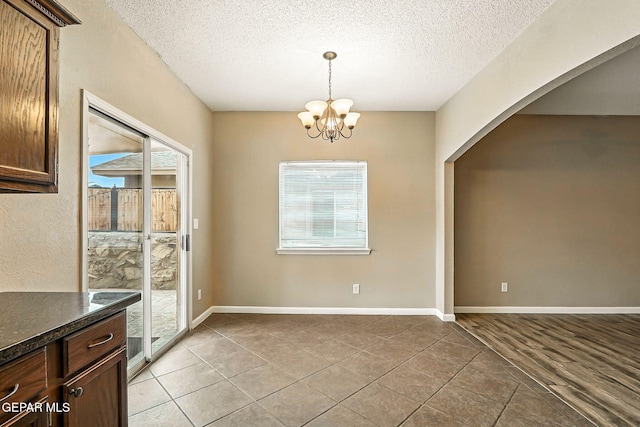 12308 Sombra Grande Dr, El Paso, TX 79938 - unfurnished dining area with a textured ceiling, light tile patterned floors, a chandelier, and arched walkways