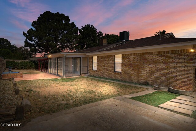 11204 Bob Mitchell Dr, El Paso, TX 79936 - back of property with a patio area, brick siding, a sunroom, a lawn, and a chimney