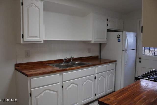 5124 Edmonton Ave, El Paso, TX 79924 - kitchen featuring wood counters, decorative backsplash, white cabinetry, and freestanding refrigerator